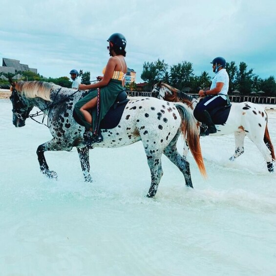 Three people riding horses on a beach. 4