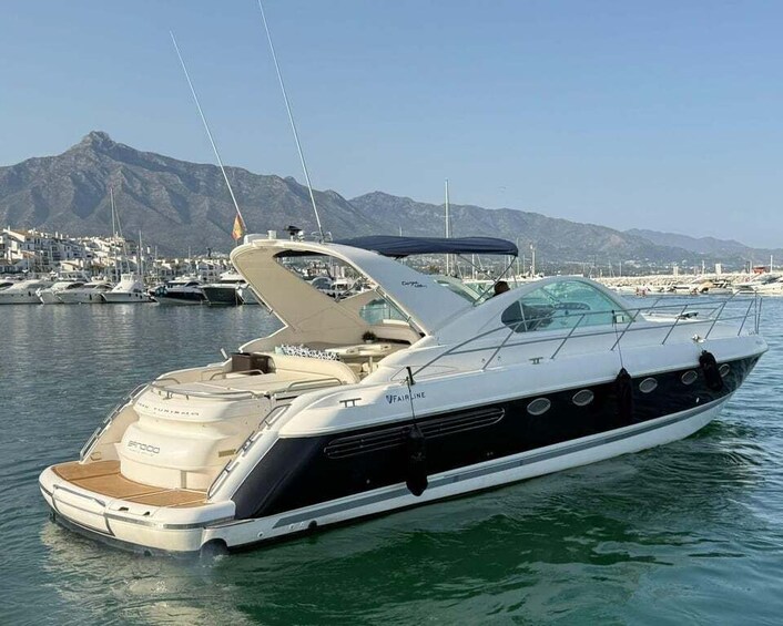A luxury yacht docked at a marina with mountains in the background. 1