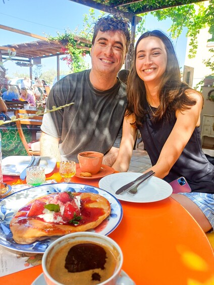 Two people sitting at an outdoor table with food and drinks. 4