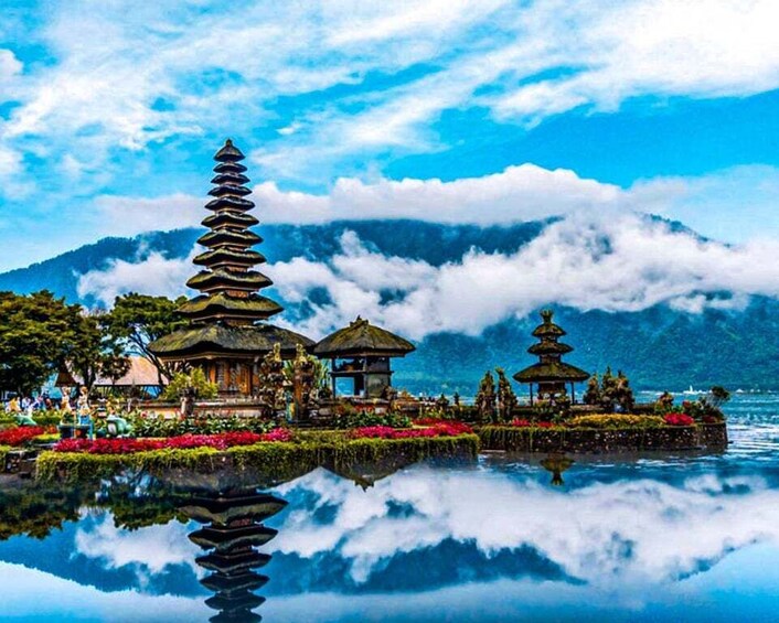 A serene temple complex with tiered pagodas and a reflective pond, surrounded by lush greenery and mountains. 4