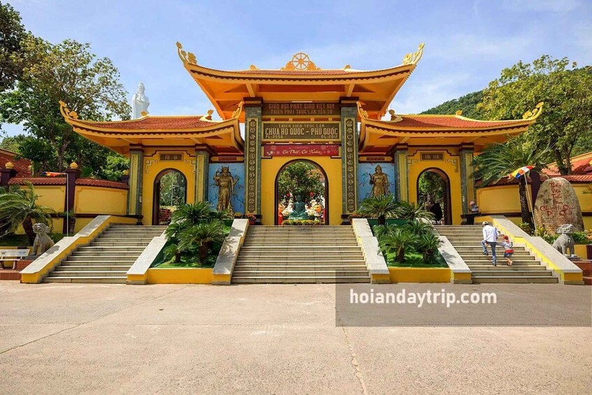 A traditional temple entrance with a golden roof, statues, and a signboard. 3