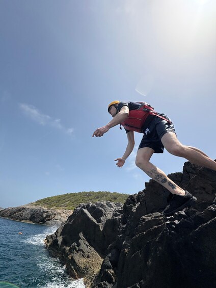 A person climbing a rocky cliff by the sea. 4