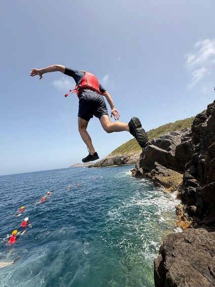 A person jumping off a rocky cliff into the sea. 3