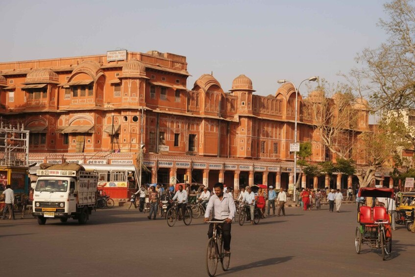 A busy street with traditional architecture, people walking, and vehicles including bicycles and rickshaws. 2