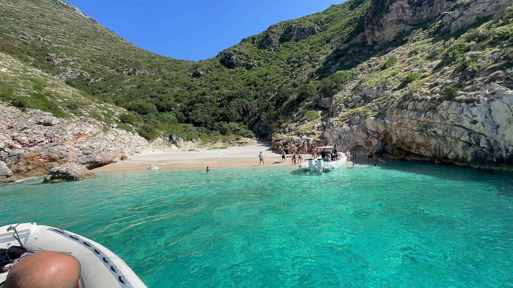 A boat on turquoise waters surrounded by rocky cliffs and a beach. 2