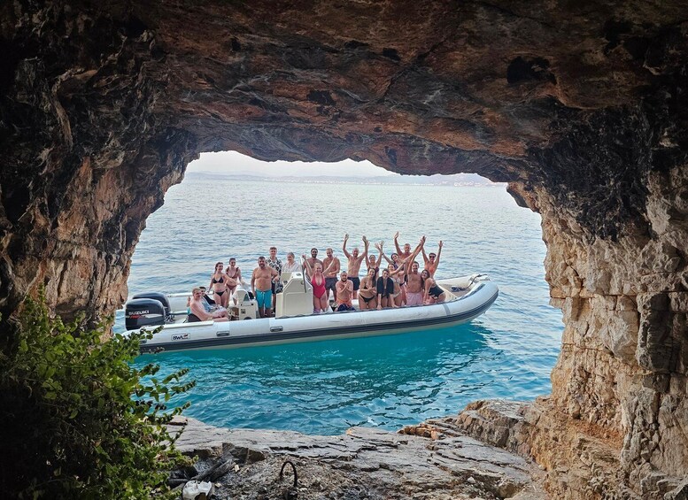 A group of people on a boat in a rocky cove with clear blue water. 1