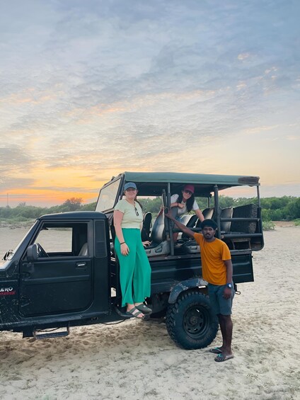 A vehicle parked on a sandy beach with a sunset in the background. 4