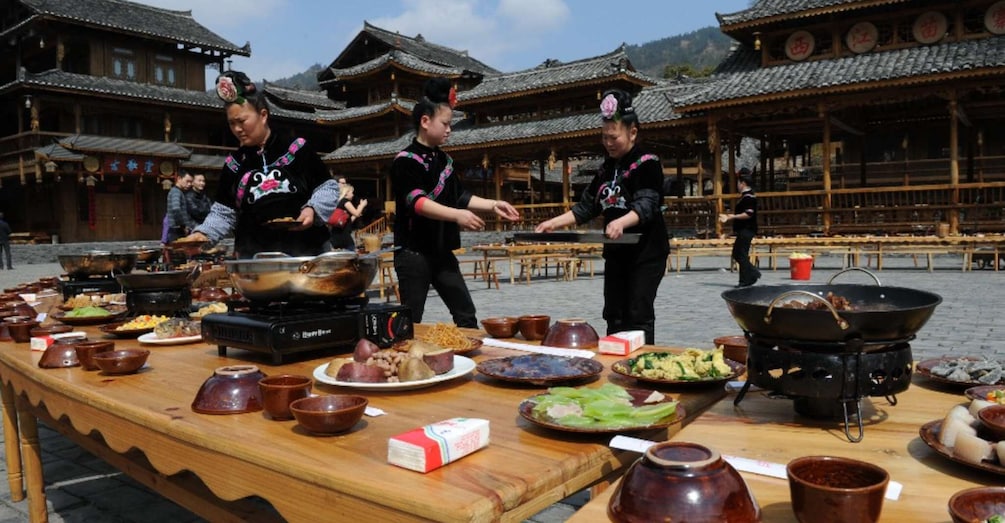 A traditional cooking scene with chefs preparing food outdoors in front of a historic building. 5