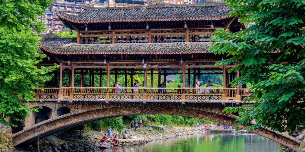 A traditional multi-tiered building with a wooden bridge over a river. 3