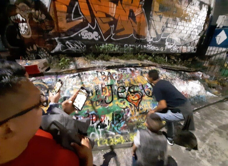 A graffiti-covered wall with people taking photos. 3