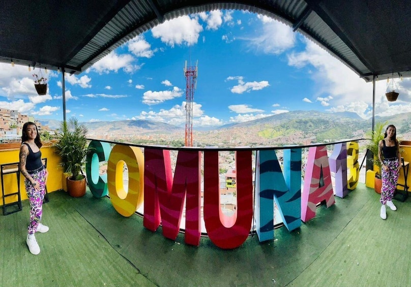 A panoramic view of a city with a large 'COMUNAS' sign in the foreground. 1