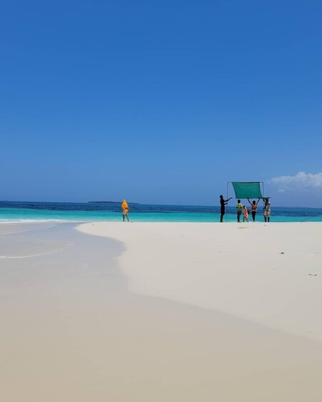 A beach with people setting up a green screen. 4