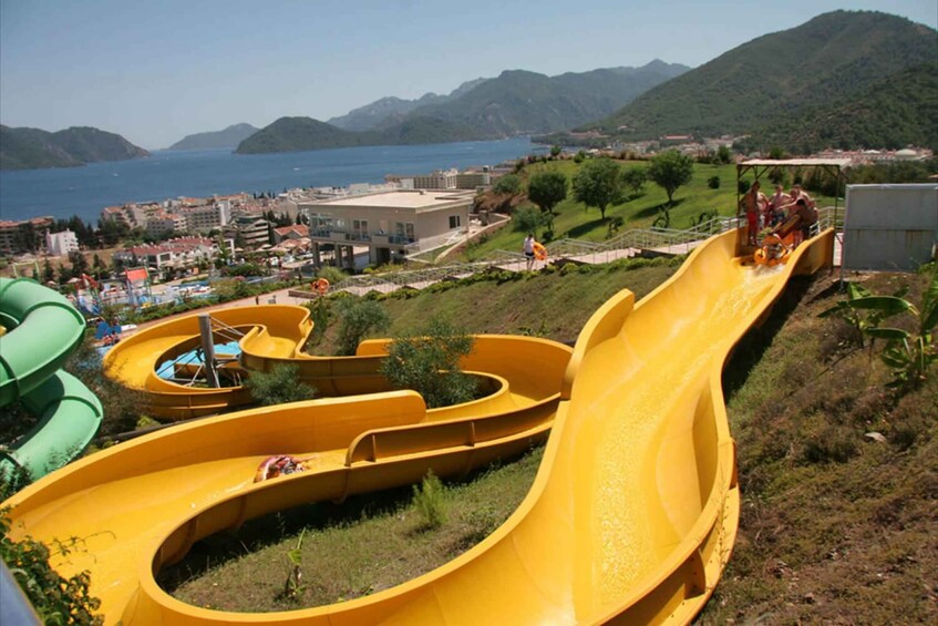 A water park with multiple slides and a view of the sea and mountains in the background. 4