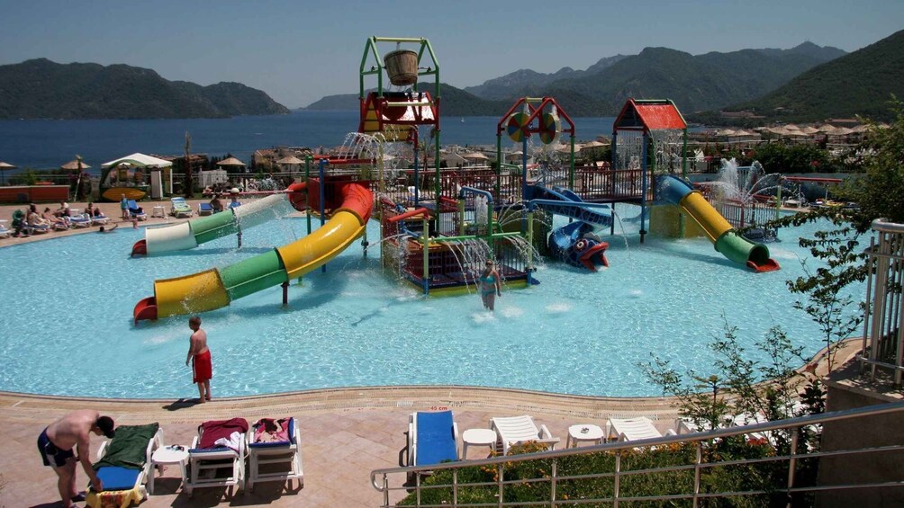 A water park with slides and water features, surrounded by a pool and lounge chairs. 2