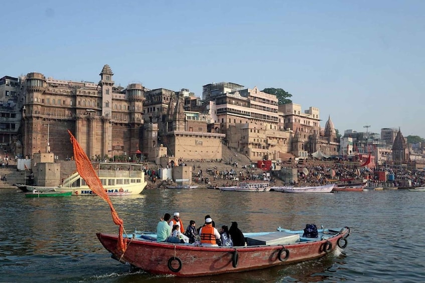 A river with boats, a historic building complex, and a crowd on the riverbank. 4