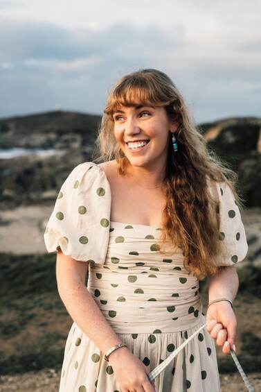 A person standing outdoors holding a string, with a landscape in the background. 5
