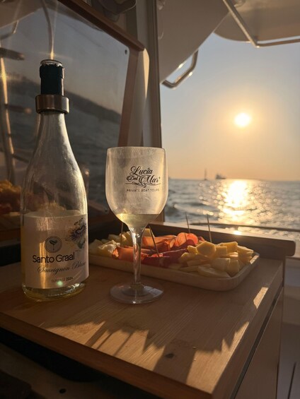 A bottle of Santo Graal wine, a glass, and a fruit platter on a boat. 2
