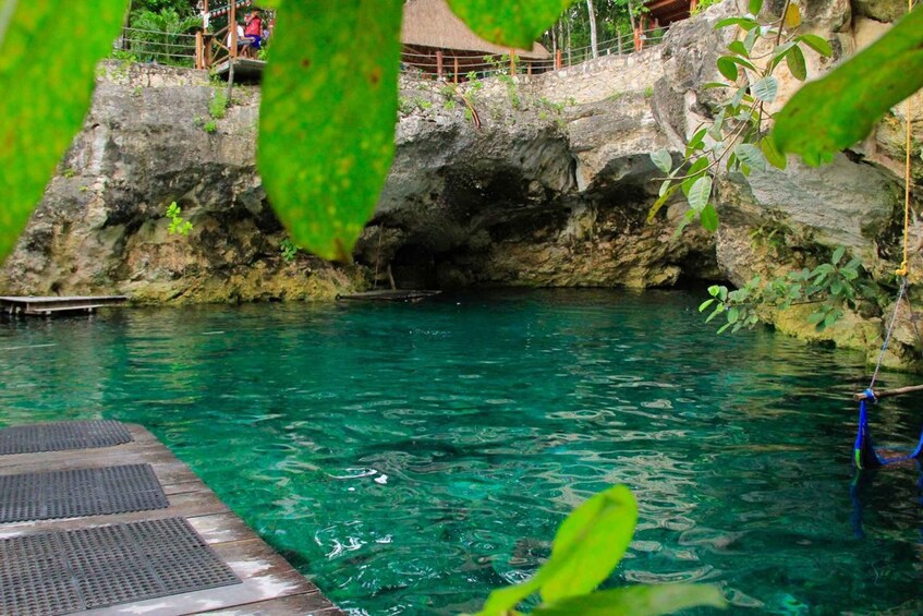 A clear pool with a wooden deck and a rocky cave backdrop. 3
