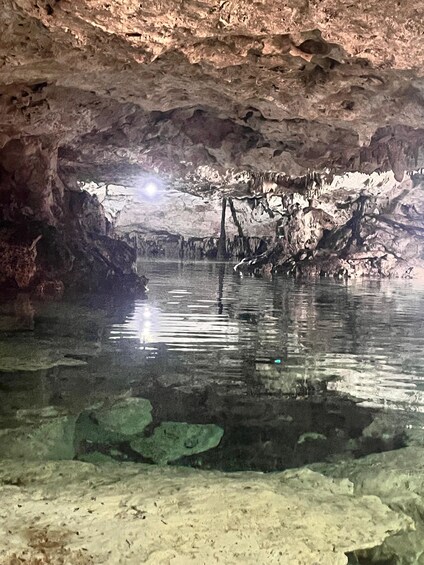 A cave interior with a clear water pool reflecting the rocky ceiling. 1