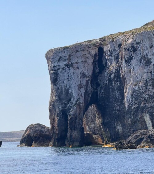 A large rock formation with a cave entrance by the sea. 5