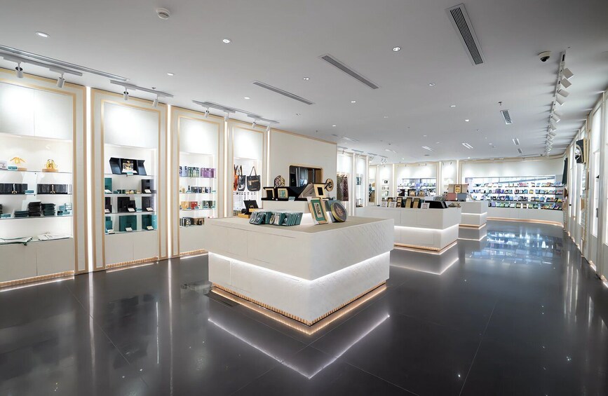 A modern, well-lit store with white and gold accents, featuring shelves of products and a central counter. 4