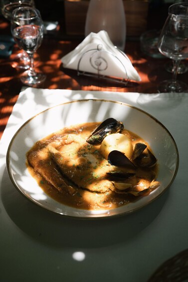 Una ciotola di zuppa di pesce con cozze e patate su un piatto bianco. 5