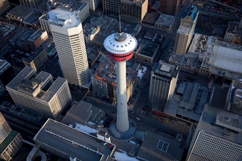A cityscape with a prominent tower featuring a red and white ring, surrounded by various buildings and streets. 1