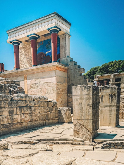 An ancient Greek temple with red columns and a blue mosaic. 1