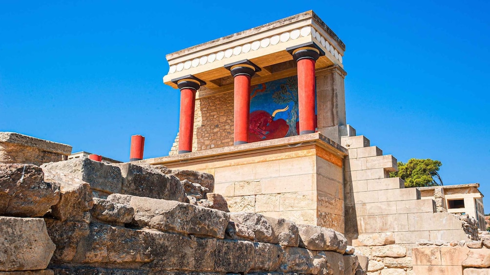 An ancient Greek temple with red columns and a colorful mural. 3