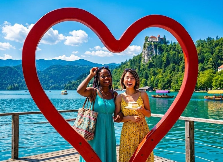 Two people standing in front of a heart-shaped structure with a lake and a castle in the background. 1