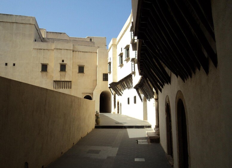 A narrow alleyway with buildings on either side, featuring arched doorways and a tiled floor. 5