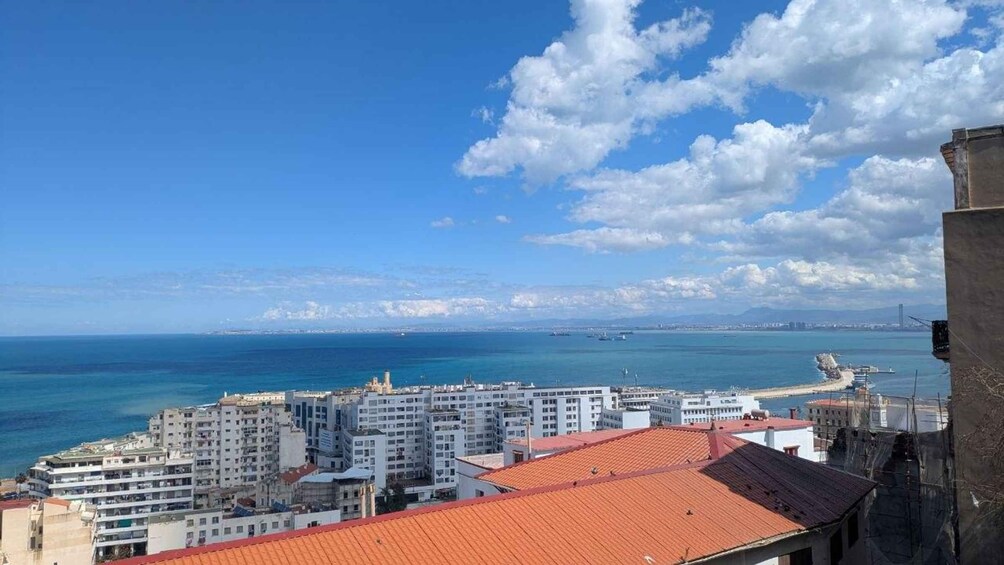A coastal cityscape with buildings, a beach, and a clear blue sky. 2