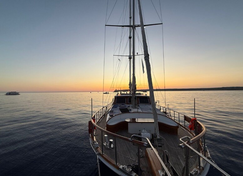 A sailboat at sunset with calm waters and a distant shoreline. 1