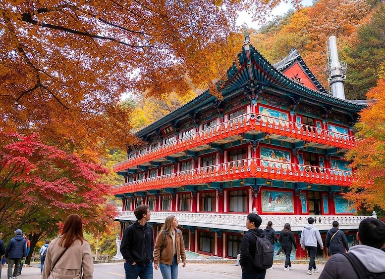 A traditional multi-story building with red and green accents, surrounded by autumn foliage. 3