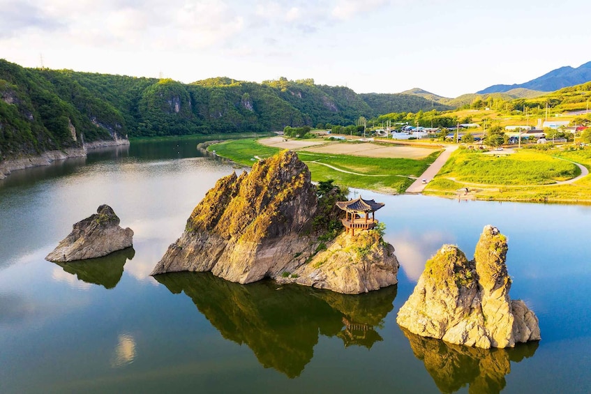 A tranquil lake with rock formations and a traditional pavilion on a small island. 4