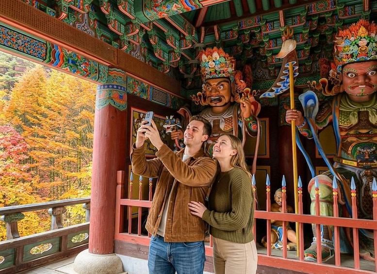 A couple taking a photo in front of a traditional building with colorful decorations and statues. 5