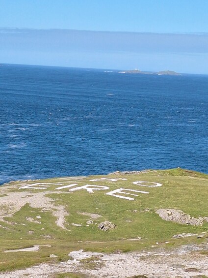 A grassy hill with the word "FREE" written on it, overlooking the ocean. 2