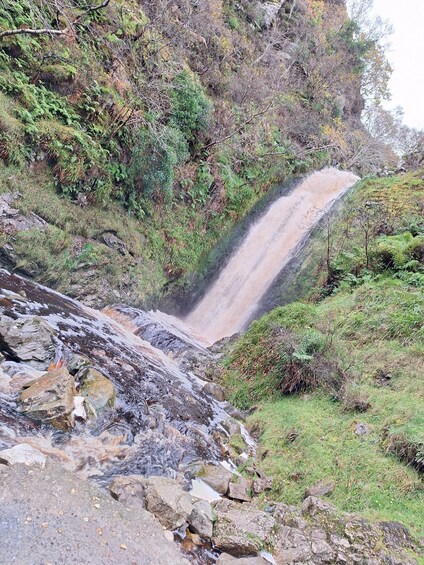 A waterfall cascading down a rocky slope surrounded by greenery. 3