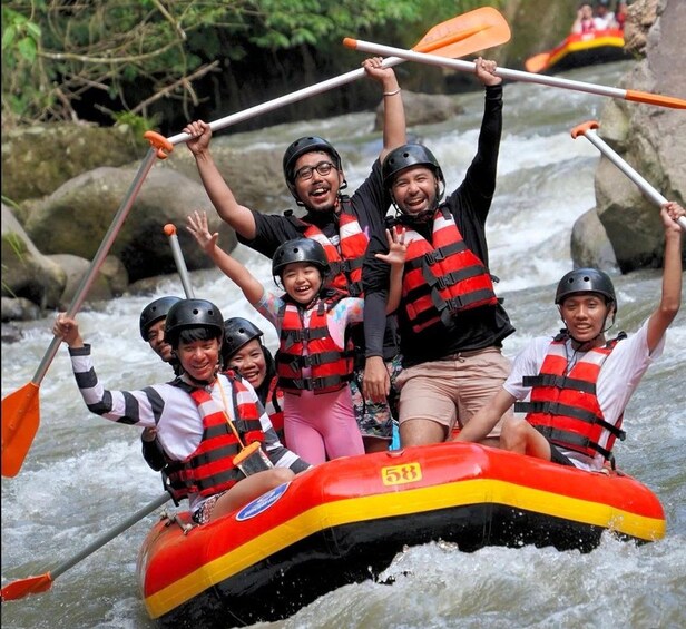 A group of people in a raft on a river, wearing life jackets and paddles. 4