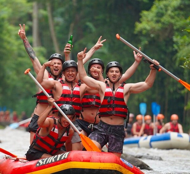 A group of people in a raft, wearing life jackets and paddles, in a river setting. 2