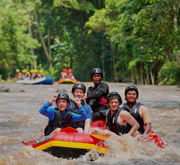 A group of people rafting on a river surrounded by trees. 1