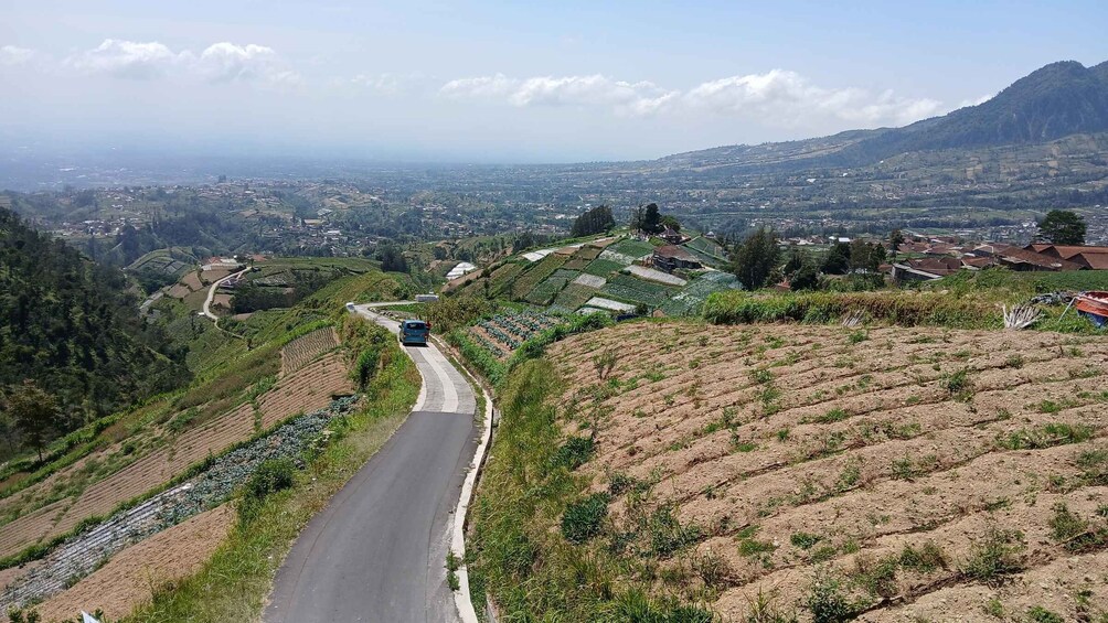 A winding road through terraced fields and a distant village. 2