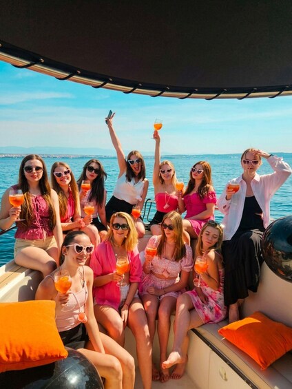 Un grupo de personas en un bote, con bebidas, y el océano al fondo. 4