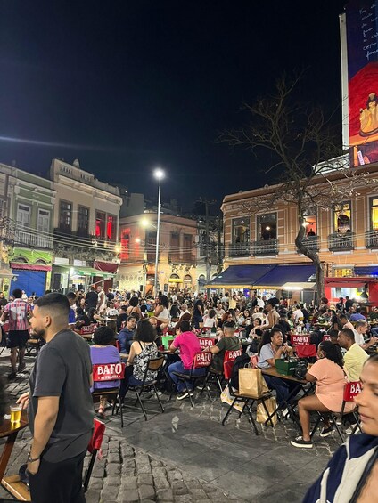 A crowded outdoor dining area at night with people seated at tables. 1