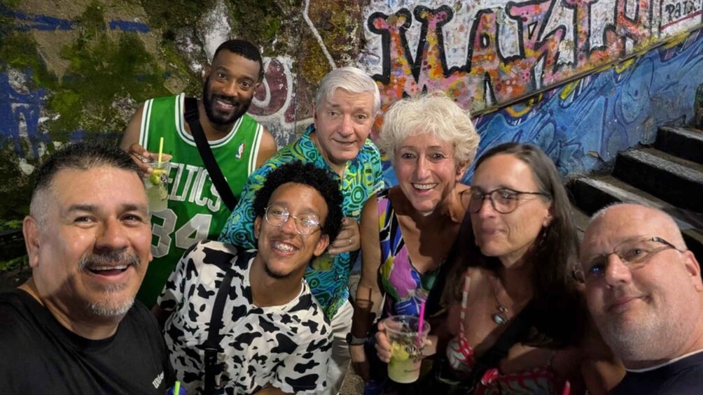 A group of people posing in front of a graffiti-covered wall with stairs. 1