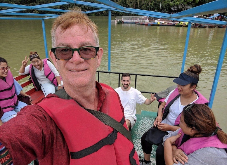 A group of people on a boat with a blue metal structure overhead. 1