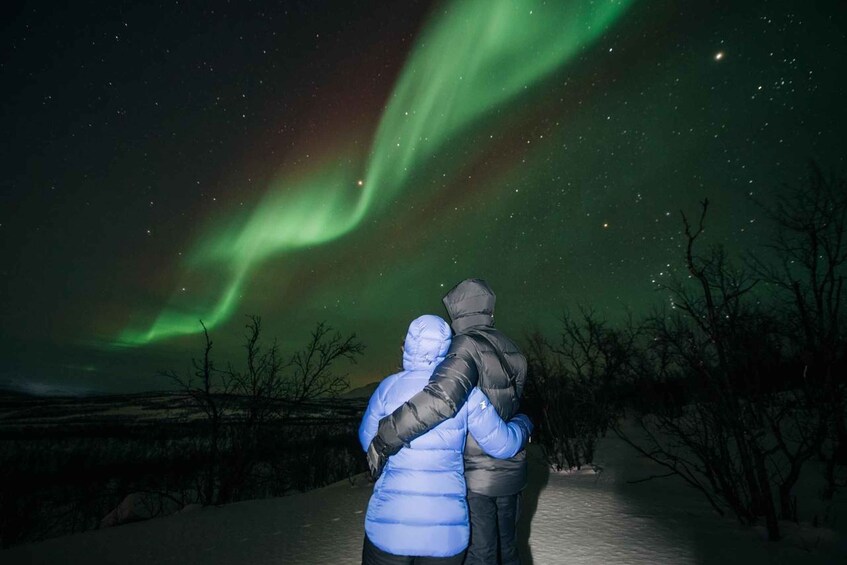 Two people embracing under a night sky with the Northern Lights. 5