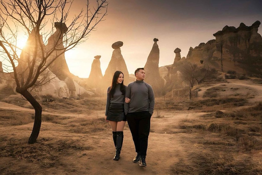 A couple walking on a dirt path with unique rock formations in the background. 2