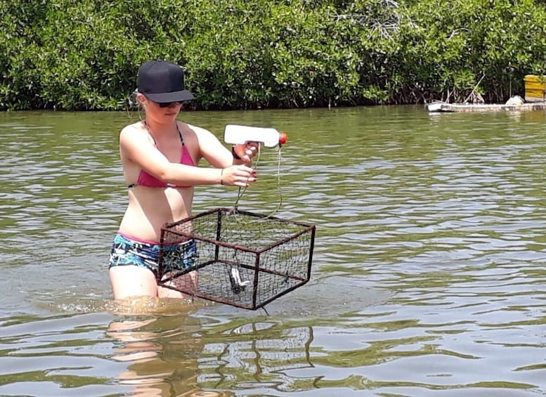 A person in a bikini holding a fishing net with a fish inside. 2