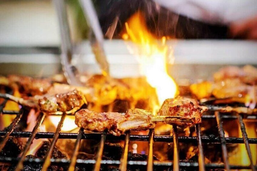 Meat being grilled on a barbecue with visible flames. 3
